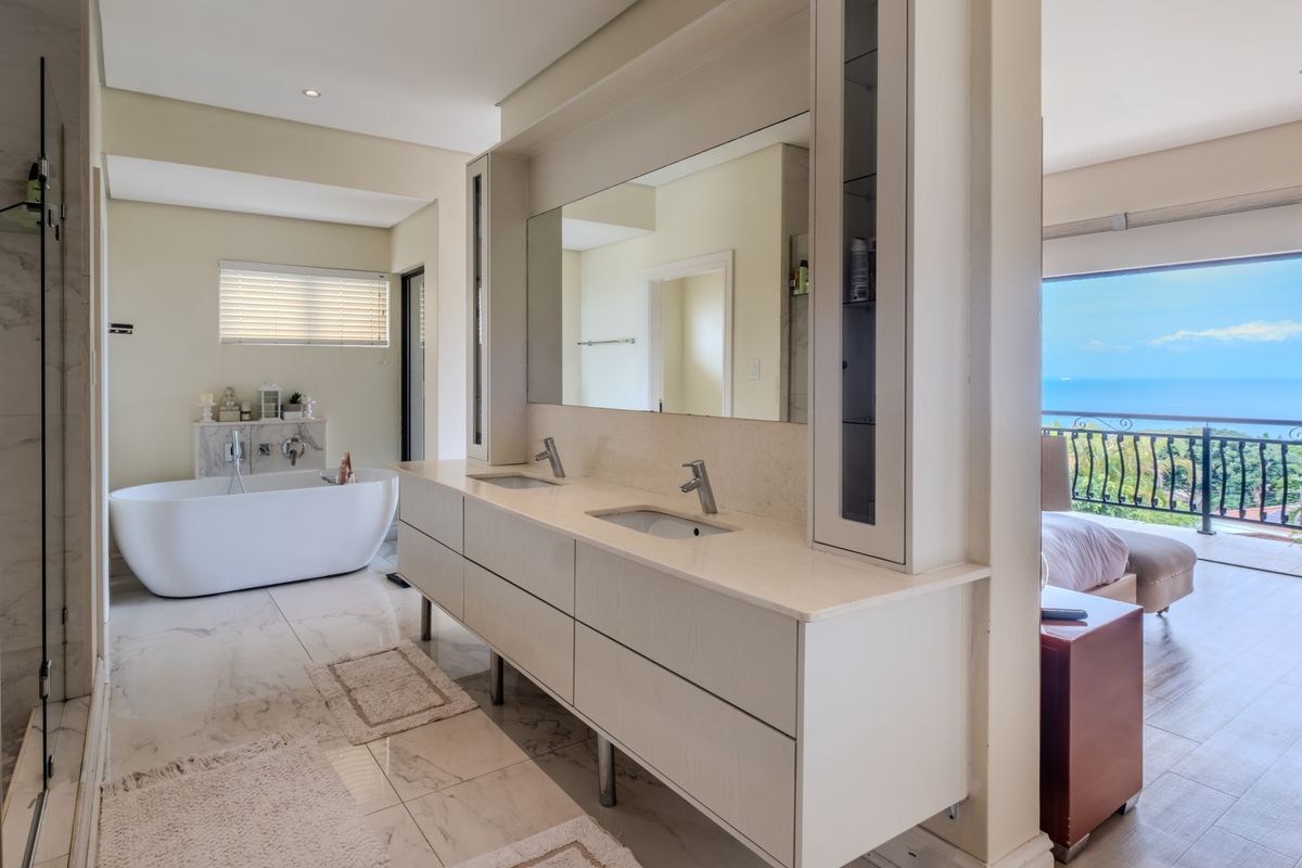 Modern en-suite bathroom featuring a double vanity, freestanding bathtub, and high-end finishes, with an open-plan layout connecting to the bedroom and ocean views.