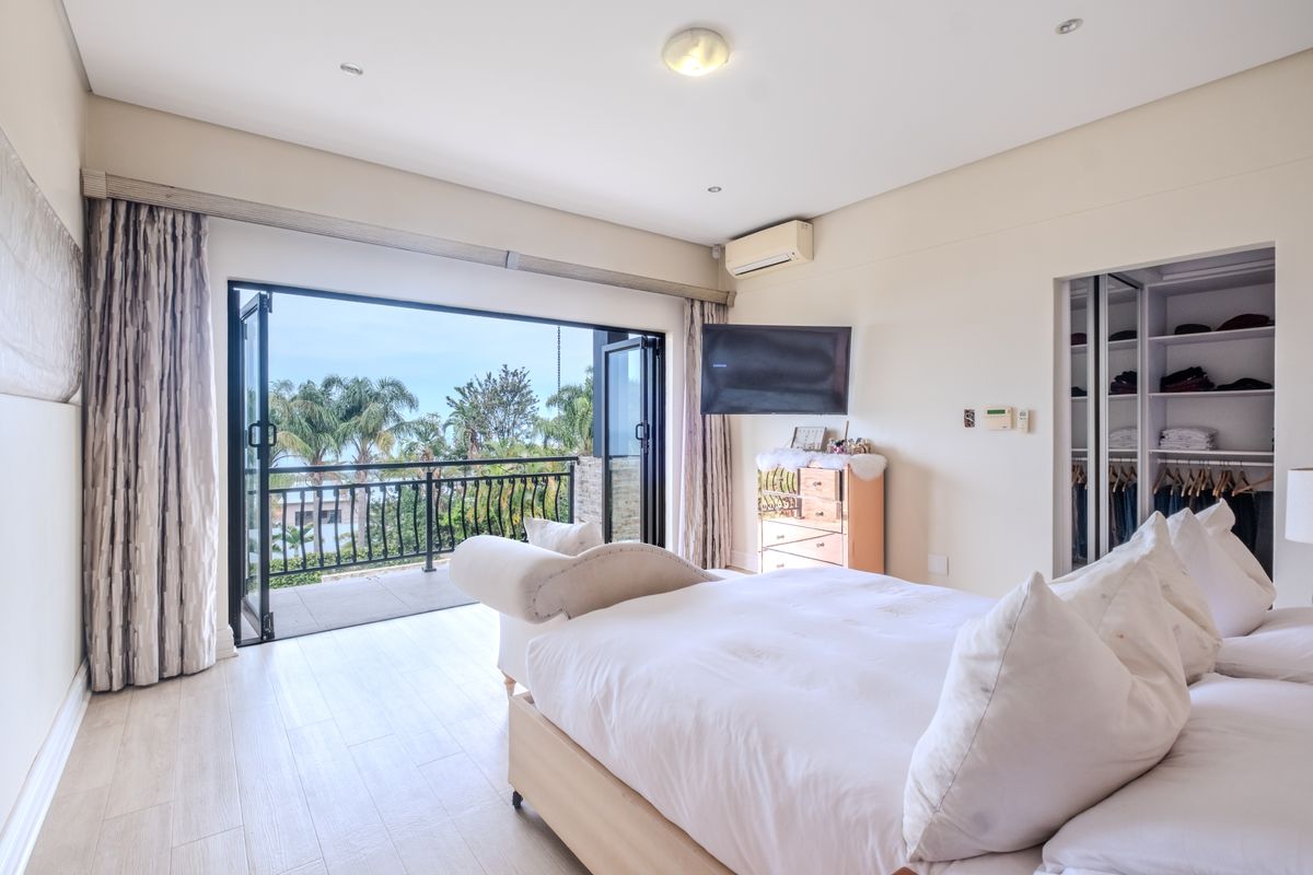Spacious bedroom featuring laminate flooring, built-in wardrobe, split-system air conditioning, and direct access to a private balcony with scenic views.