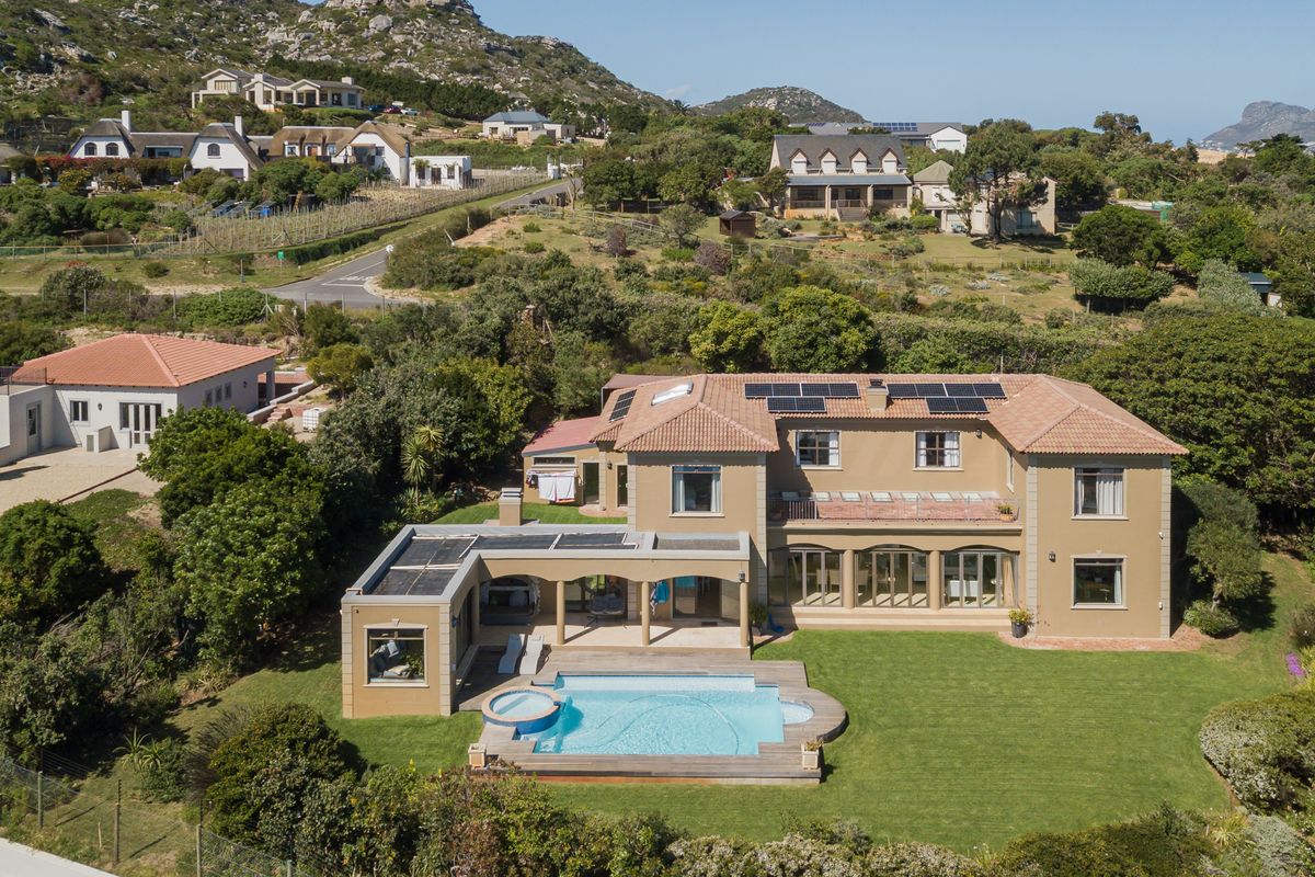 Aerial view of a large residential property featuring a swimming pool, expansive lawn, solar panels, and a covered patio area.