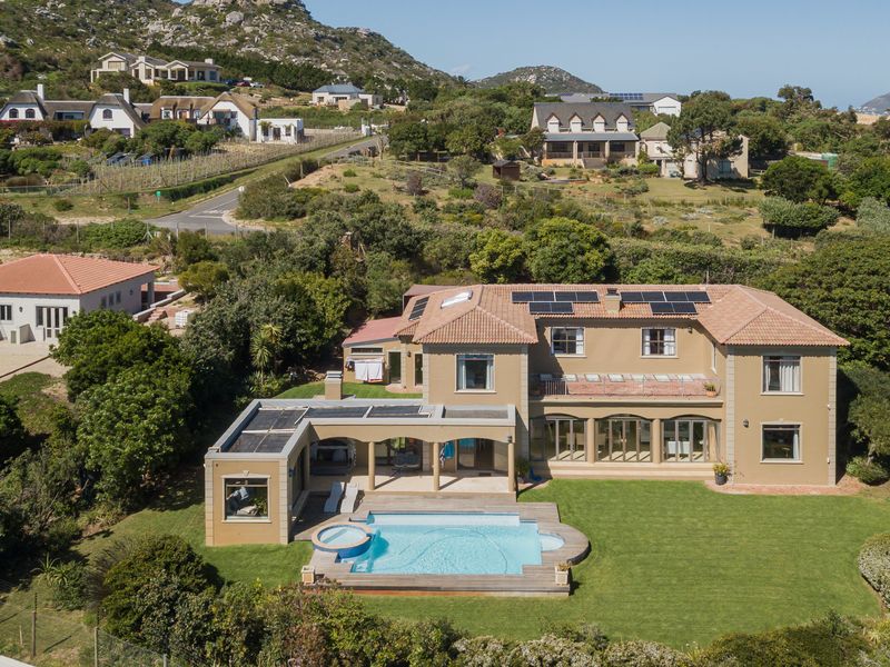 Aerial view of a large residential property featuring a swimming pool, expansive lawn, solar panels, and a covered patio area.