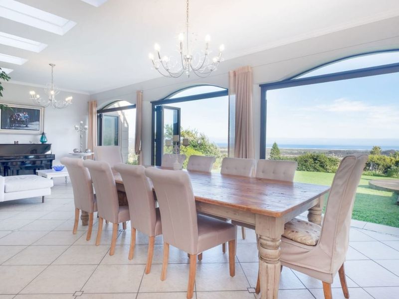 Spacious dining room featuring large arched glass doors with scenic views, tiled flooring, and elegant chandeliers, creating a bright and airy atmosphere.