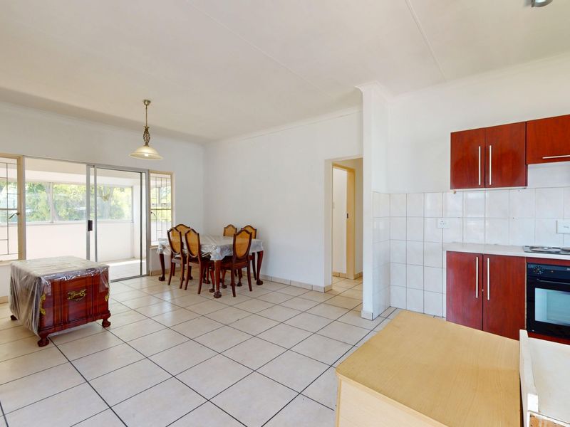 Open-plan living and kitchen area featuring tiled flooring, built-in cabinetry with oven and hob, and sliding door access to the patio.