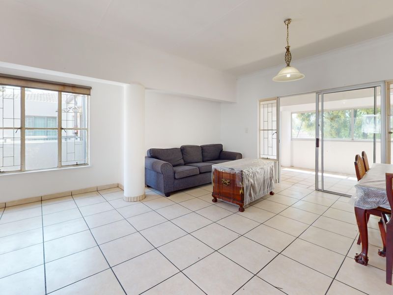 Spacious open-plan living and dining area featuring ceramic tiled flooring, a structural column, and sliding glass doors leading to an enclosed patio.