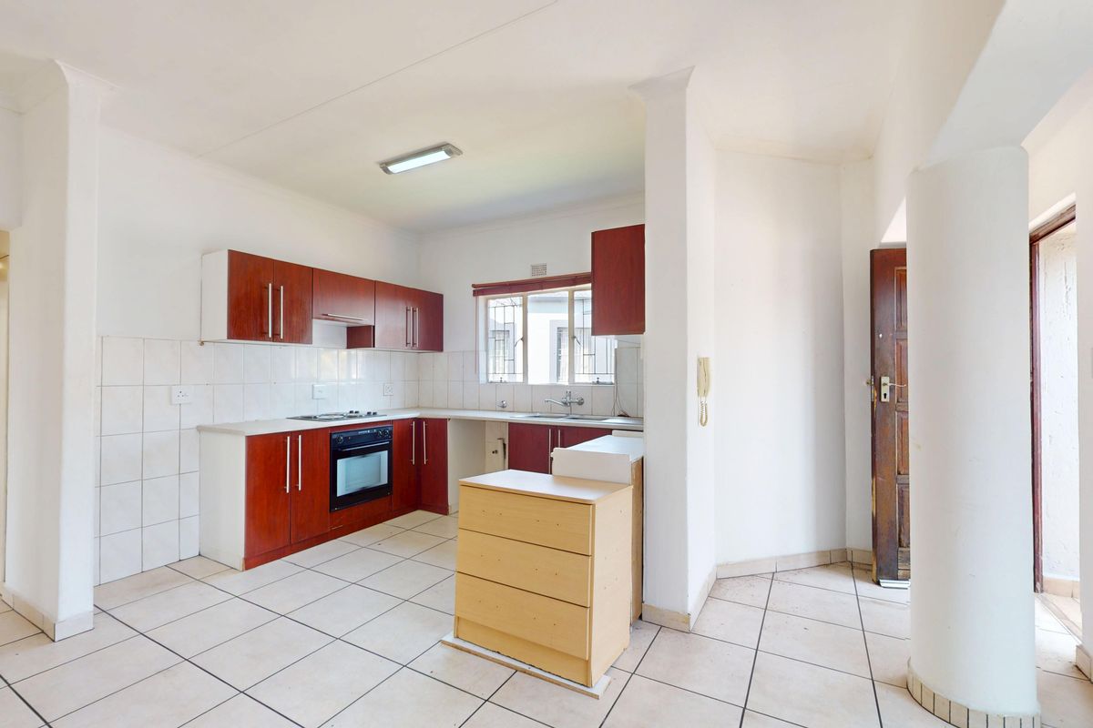 A functional kitchen featuring built-in wooden cabinetry, an integrated oven and hob, tiled flooring, and a double sink with a tiled backsplash.