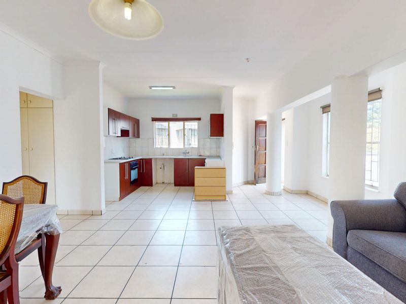 Spacious open-plan living and kitchen area featuring tiled flooring, built-in cabinetry, and functional kitchen appliances, offering a versatile layout for modern living.