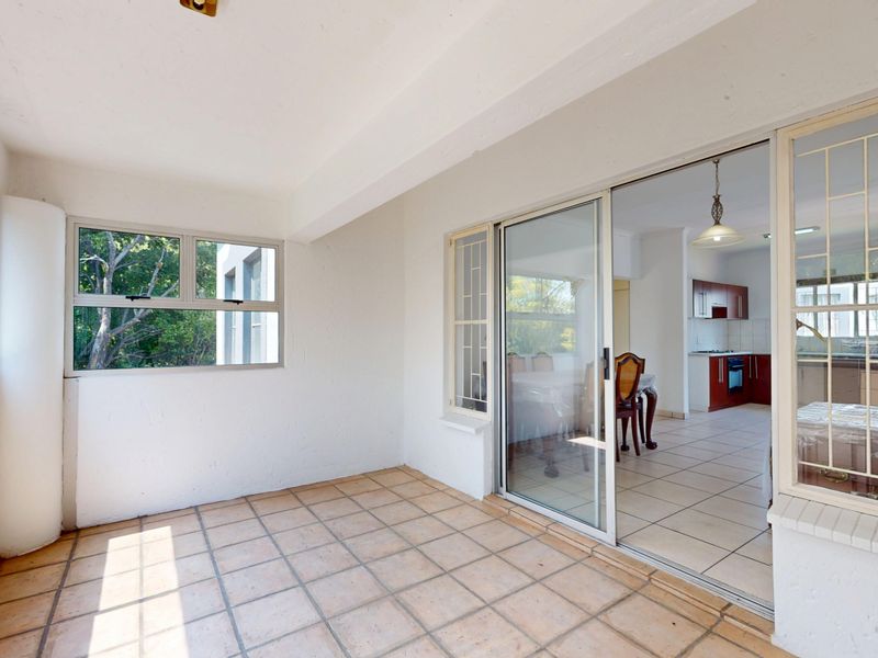 A covered patio area with tiled flooring and sliding glass doors providing access to the interior living space.
