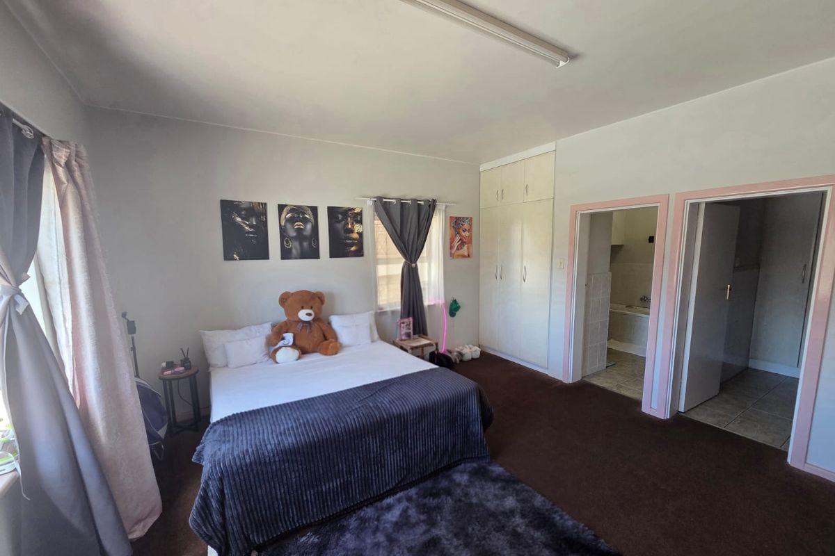 Spacious bedroom featuring built-in wardrobes, carpeted flooring, and direct access to an en-suite bathroom.