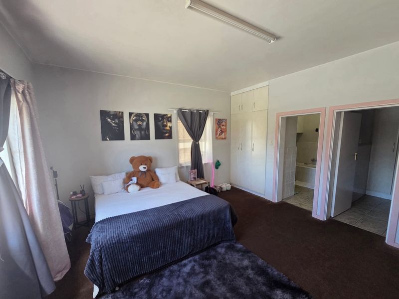 Spacious bedroom featuring built-in wardrobes, carpeted flooring, and direct access to an en-suite bathroom.
