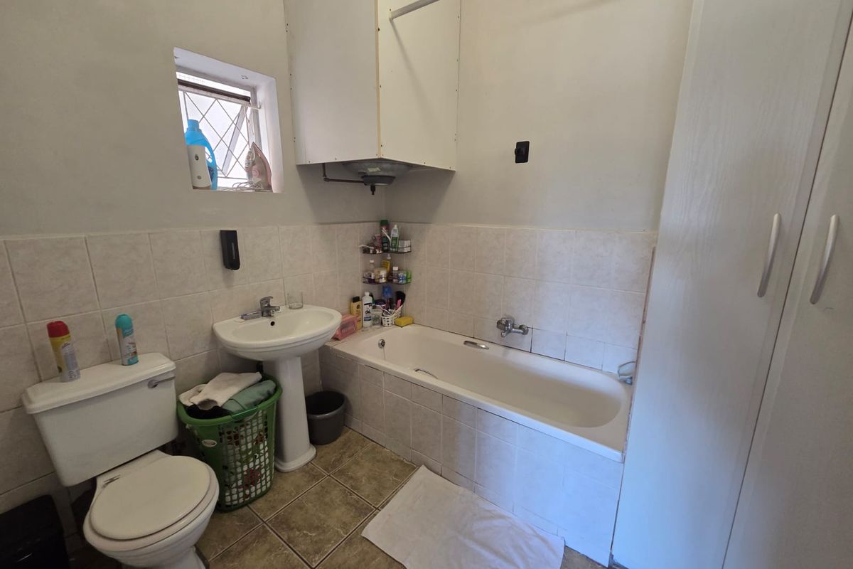 A functional bathroom featuring a pedestal basin, built-in bathtub, tiled finishes, and built-in storage cabinetry.