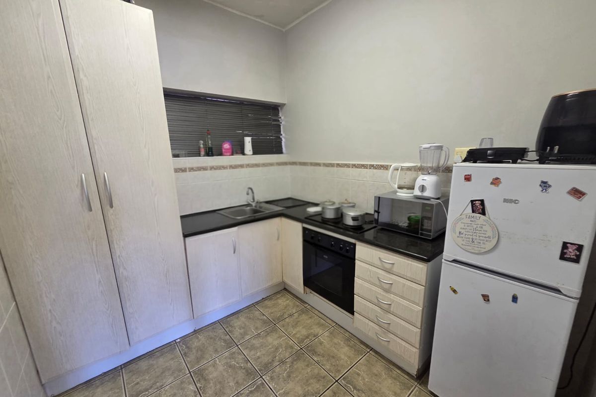 A functional kitchen featuring built-in cabinetry, laminate countertops, a built-in oven, and a hob, with tiled flooring and a tiled backsplash.