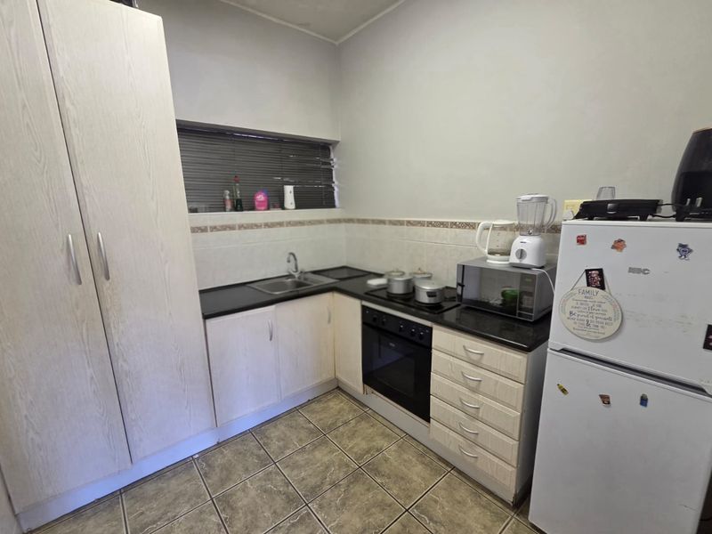 A functional kitchen featuring built-in cabinetry, laminate countertops, a built-in oven, and a hob, with tiled flooring and a tiled backsplash.