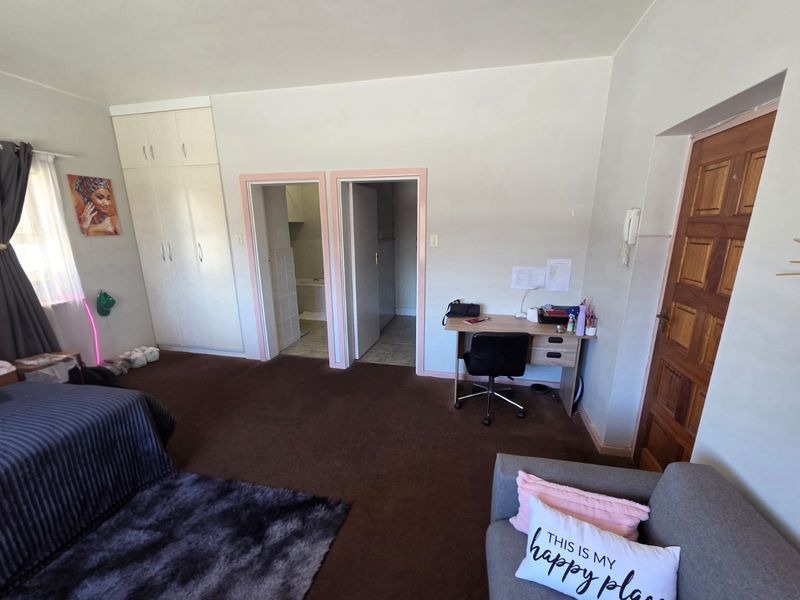 A bedroom featuring built-in cupboards, carpeted flooring, and direct access to an en-suite bathroom.
