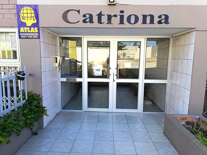 The entrance to the Catriona apartment building features double glass doors, tiled flooring, and an intercom system, providing secure access to the complex.