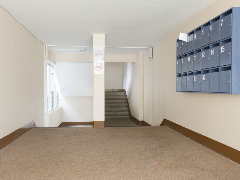 Apartment building entrance foyer featuring a bank of wall-mounted mailboxes and access to a concrete staircase.