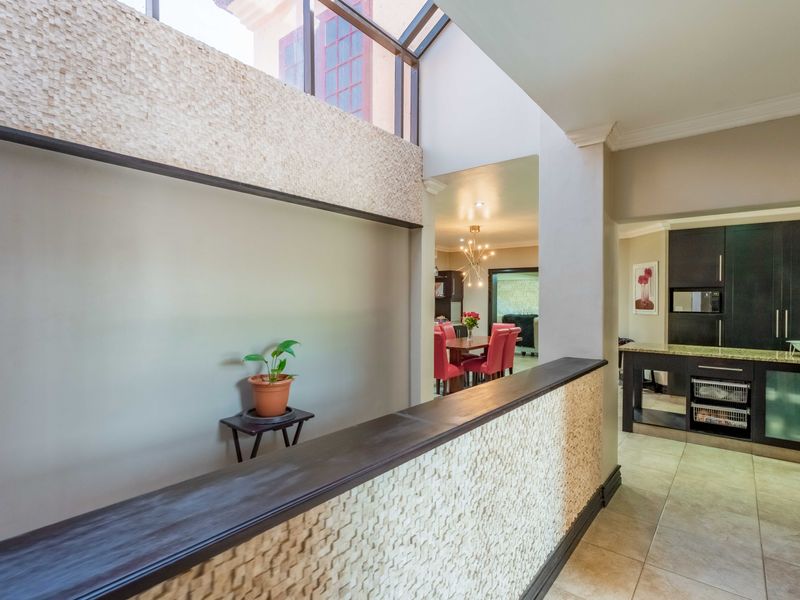 Spacious open-plan living area featuring a striking textured stone feature wall, skylight, and a modern kitchen with granite countertops and ample cabinetry.