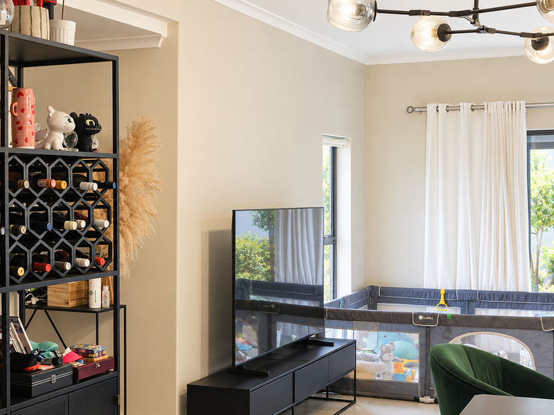 A bright and modern living room featuring a contemporary chandelier, large windows, and a sliding door leading to the outdoor area.