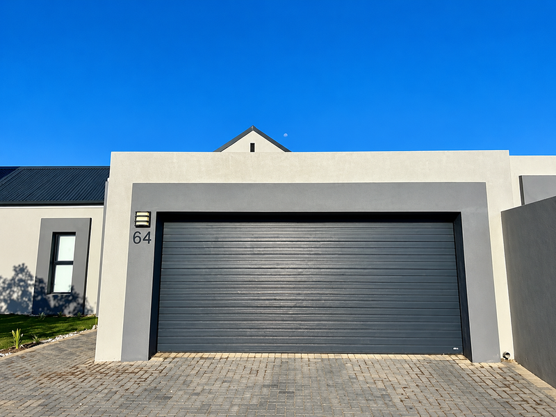 Modern front facade featuring a sleek automated garage door, paved driveway, and contemporary architectural finishes with clean lines.