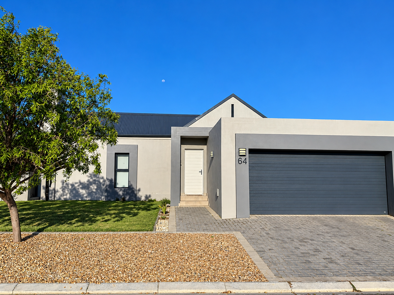 Modern single-story residential home featuring a clean plastered facade, dark metal roof, paved driveway, and a spacious double garage.