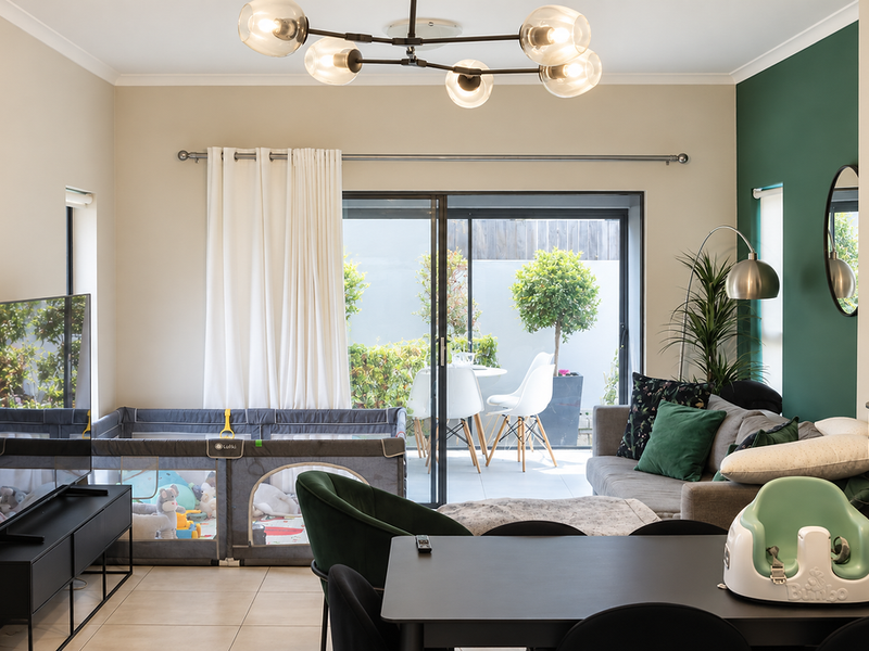 A well-lit living room featuring tiled floors, a modern chandelier, and large sliding glass doors that provide direct access to the outdoor patio area.