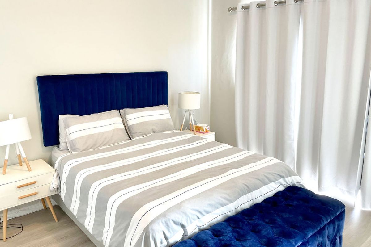 A bright and well-maintained bedroom featuring light-toned laminate flooring and neutral wall finishes.