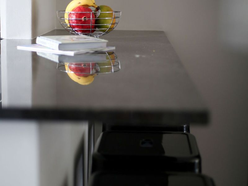 A close-up view of a sleek, dark stone breakfast bar countertop in a modern kitchen setting.
