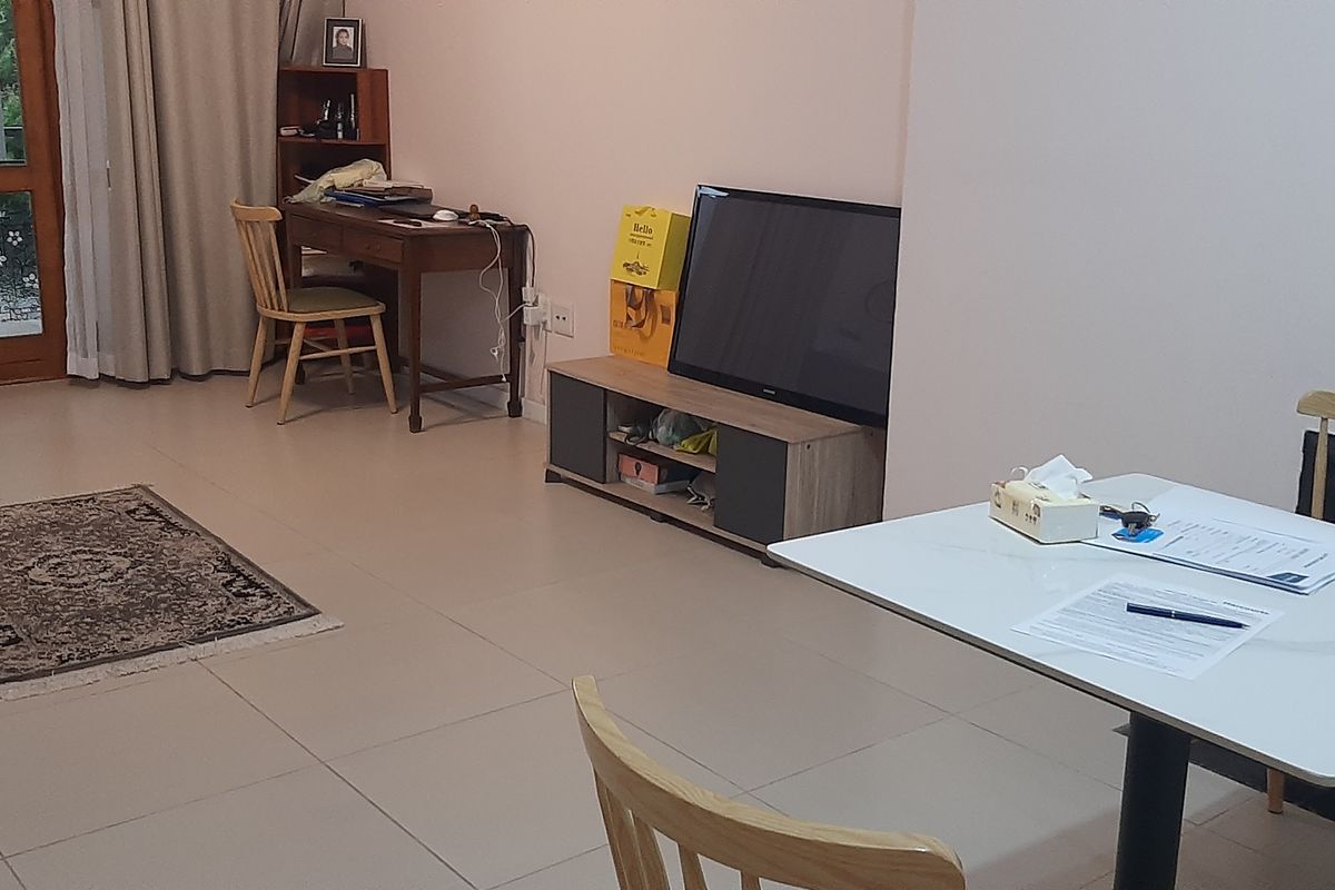 A living area featuring neutral tiled flooring and a glass-panelled door leading to an outdoor space, providing a functional and well-lit living environment.