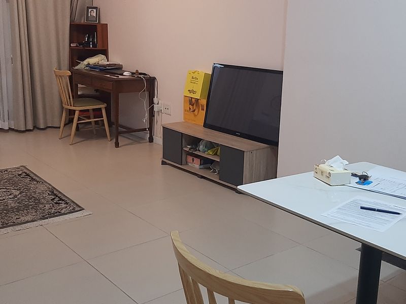 A living area featuring neutral tiled flooring and a glass-panelled door leading to an outdoor space, providing a functional and well-lit living environment.
