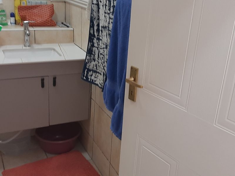A compact bathroom featuring a wall-mounted vanity cabinet with a basin, mixer tap, and neutral wall tiling.