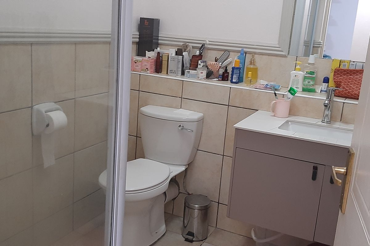 A functional bathroom featuring a shower enclosure, a wall-mounted vanity with a basin, and tiled wall finishes.
