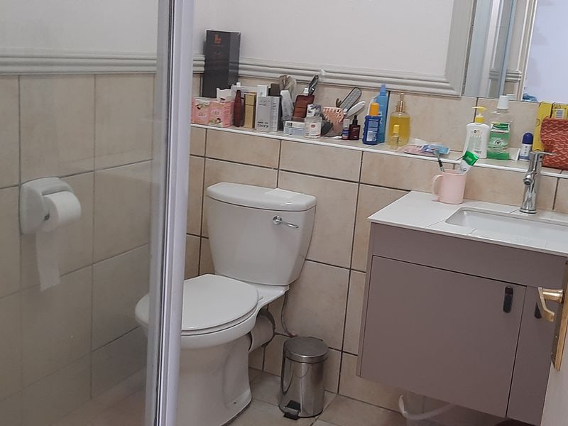 A functional bathroom featuring a shower enclosure, a wall-mounted vanity with a basin, and tiled wall finishes.