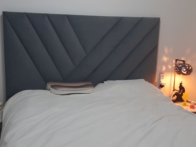A cozy bedroom featuring a modern, dark grey upholstered headboard with a geometric pattern.
