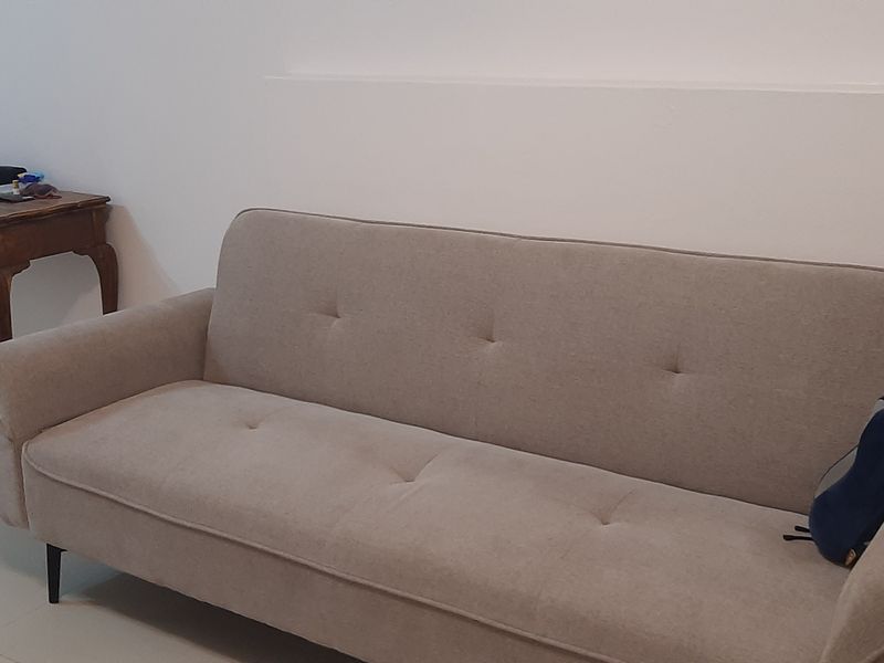 A simple living room area featuring neutral tiled flooring and plain walls, providing a blank canvas for interior design.
