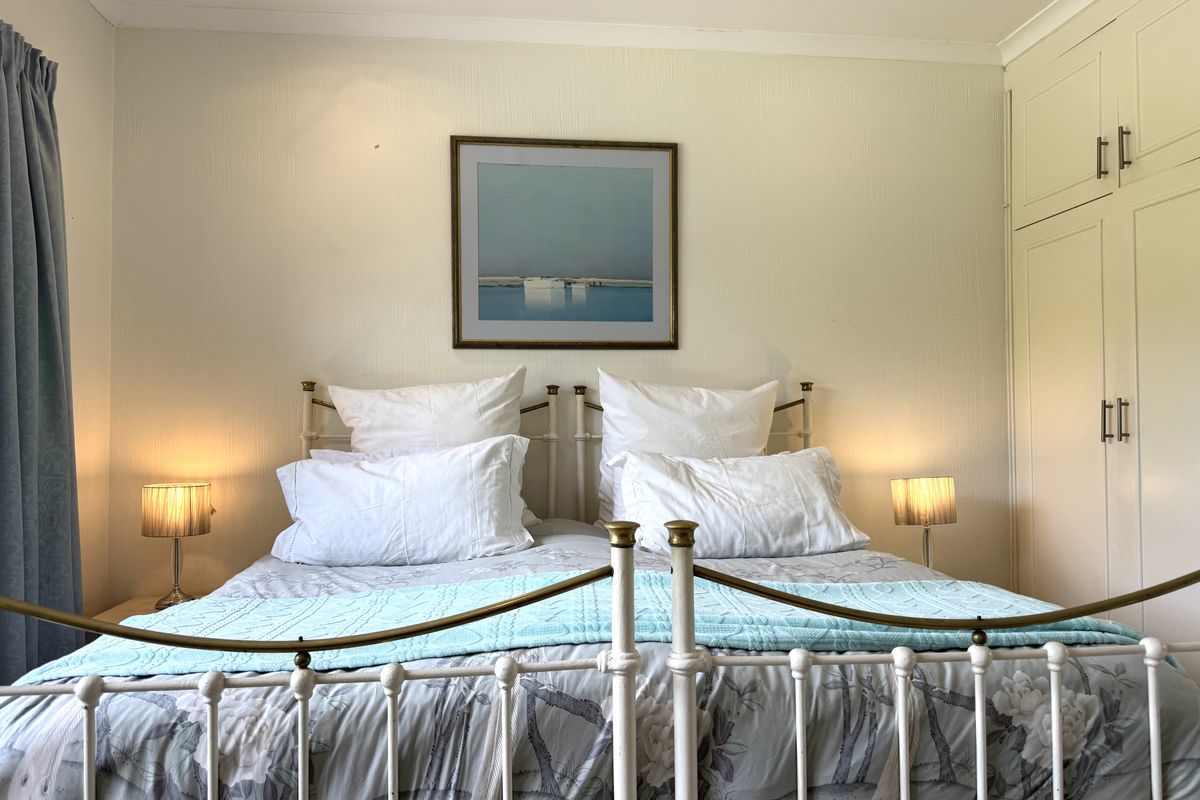 A cozy bedroom featuring built-in cupboards and recessed downlighting, providing a functional and well-lit sleeping space.
