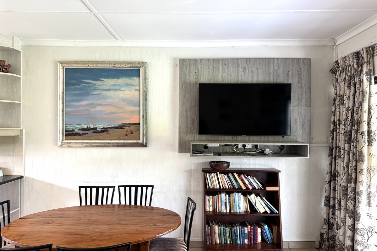 A living area featuring tiled flooring and a built-in television wall panel, providing a functional space for relaxation and entertainment.