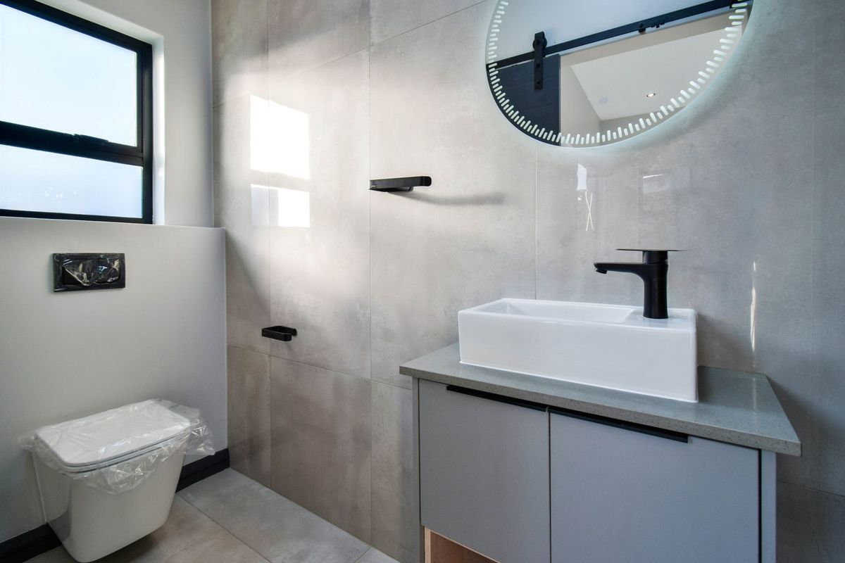 Modern bathroom featuring a sleek vanity with a vessel sink, wall-mounted toilet, and contemporary grey tiling.