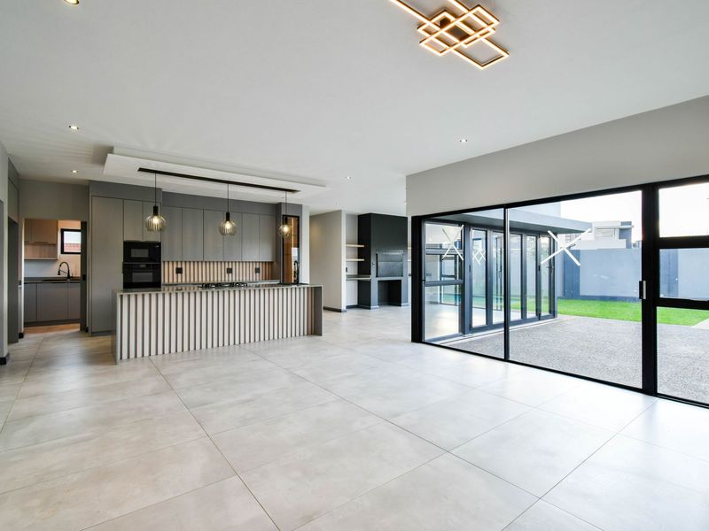 Modern open-plan living area featuring a sleek kitchen with integrated appliances, a scullery, and large sliding doors opening to the rear garden.