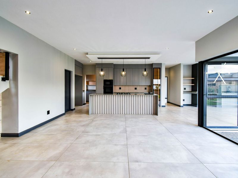 Modern open-plan kitchen featuring a central island with slatted timber detailing, integrated cabinetry, built-in oven, and large format floor tiles.