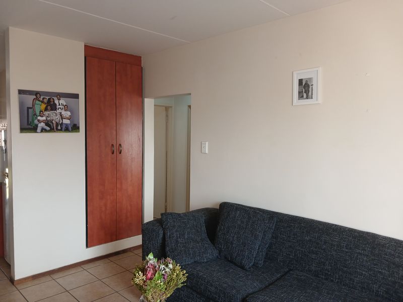 A living room area featuring tiled flooring and a built-in wooden cupboard, providing functional storage space within the home.