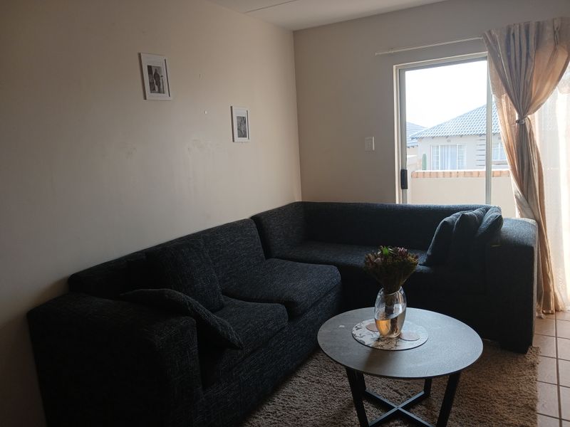 A living room area featuring tiled flooring and a sliding glass door providing access to the exterior.