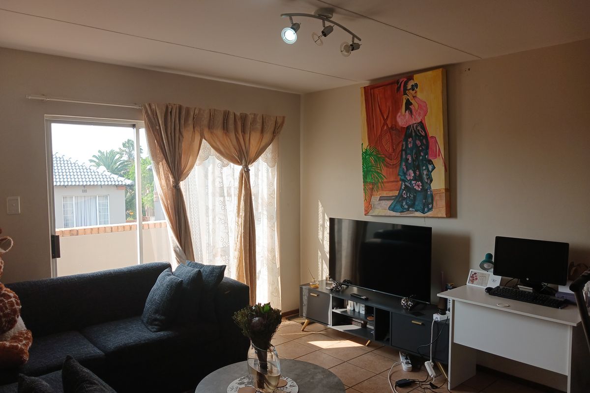 A comfortable living room featuring tiled flooring, track lighting, and a sliding glass door providing access to an outdoor area.