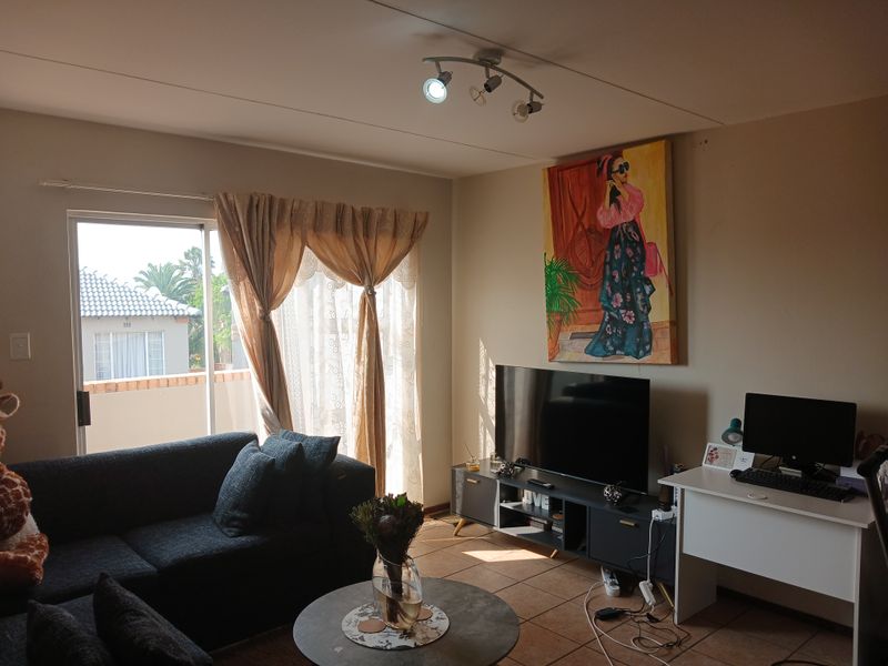 A comfortable living room featuring tiled flooring, track lighting, and a sliding glass door providing access to an outdoor area.