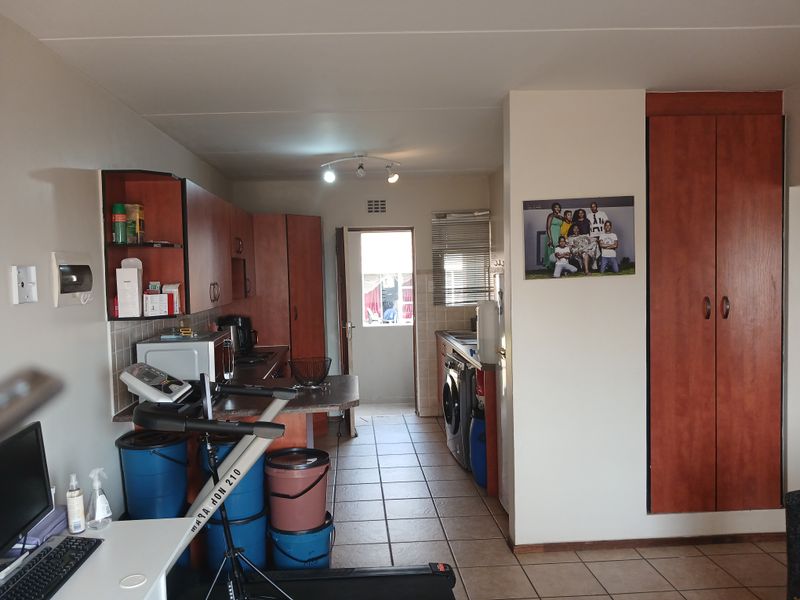 A functional kitchen area featuring built-in cabinetry, tiled flooring, and a tiled backsplash, providing a practical layout for daily use.