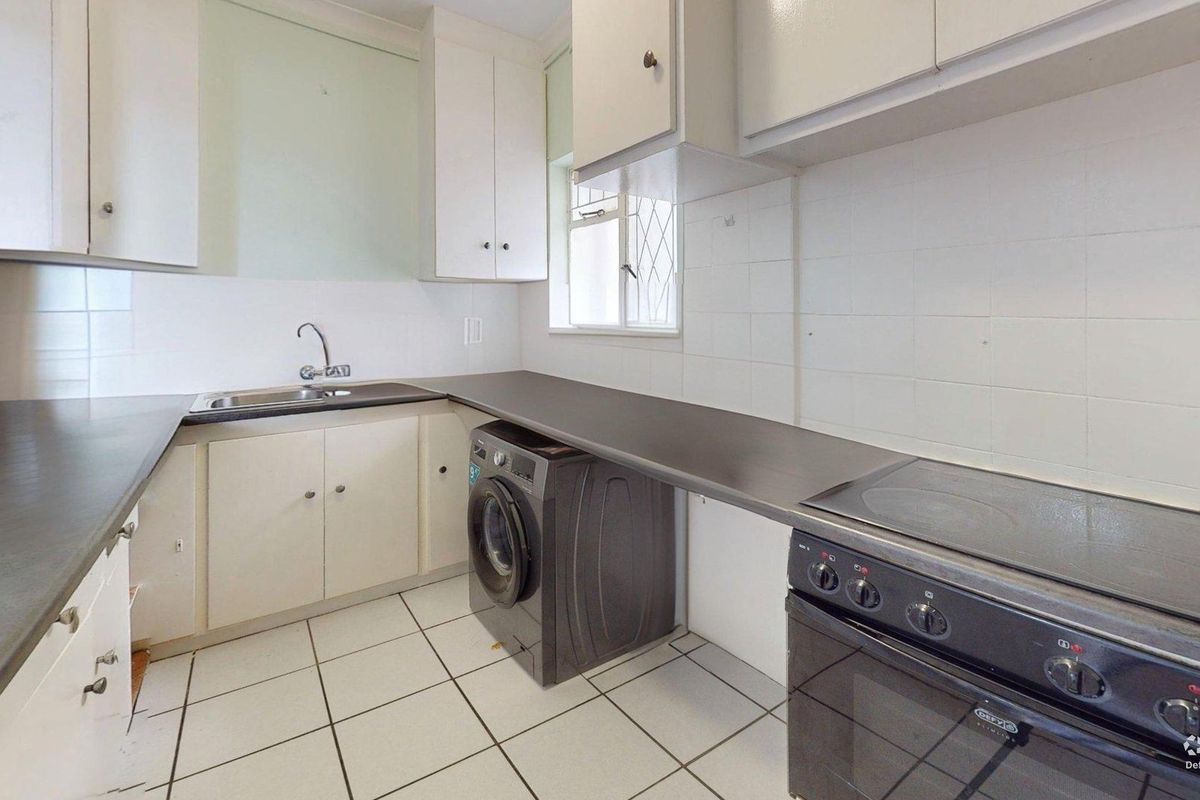 A functional kitchen featuring built-in cabinetry, laminate countertops, a stainless steel sink, and an electric stove with tiled flooring and walls.