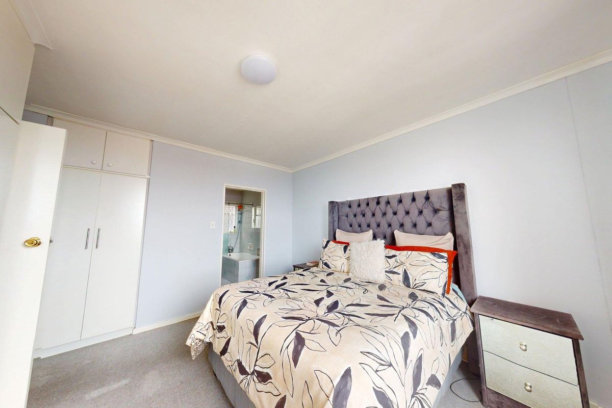 A well-lit bedroom featuring built-in cupboards, carpeted flooring, and direct access to an en-suite bathroom.