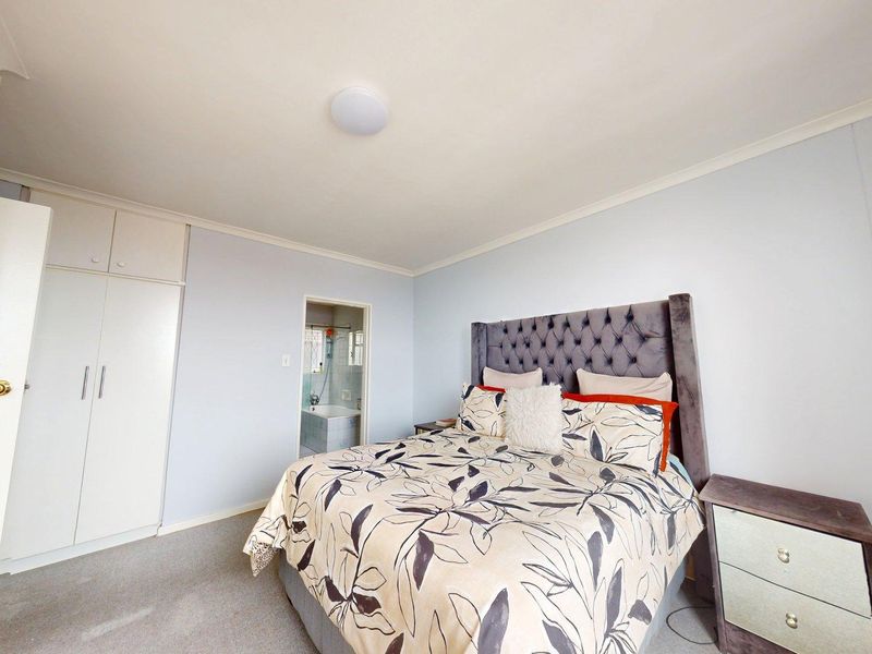 A well-lit bedroom featuring built-in cupboards, carpeted flooring, and direct access to an en-suite bathroom.