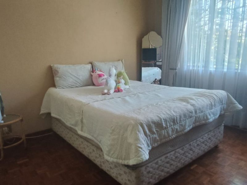 A bedroom featuring classic parquet flooring and a large window allowing for natural light.