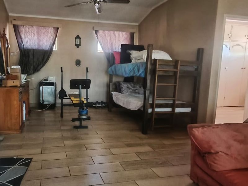 Spacious bedroom featuring tiled flooring, a ceiling fan, and access to built-in storage areas.