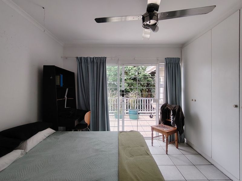 Bedroom featuring built-in cupboards, a ceiling fan, and sliding glass doors providing access to an outdoor patio area.