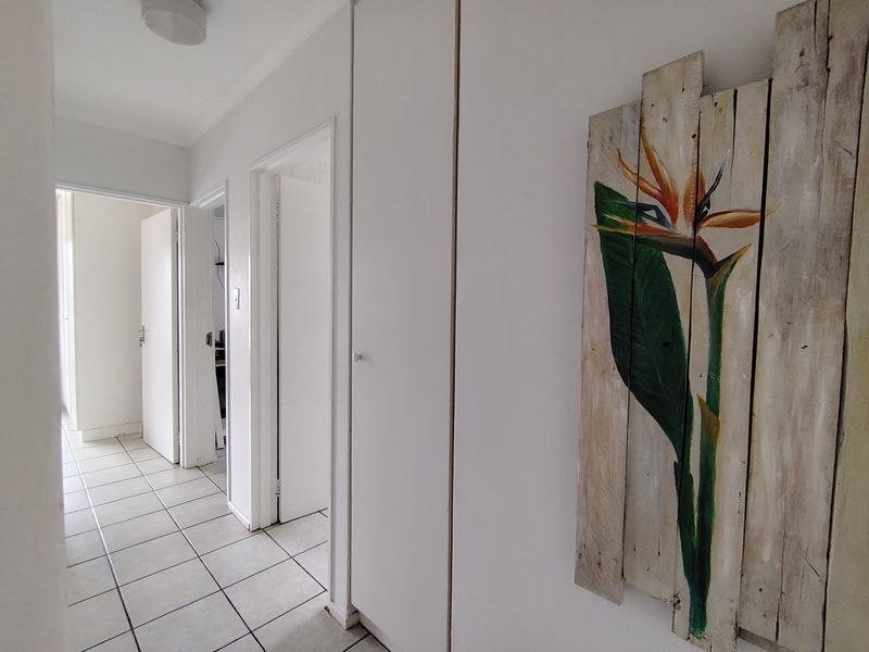 A bright, tiled hallway featuring built-in storage cupboards and access to multiple rooms within the apartment.