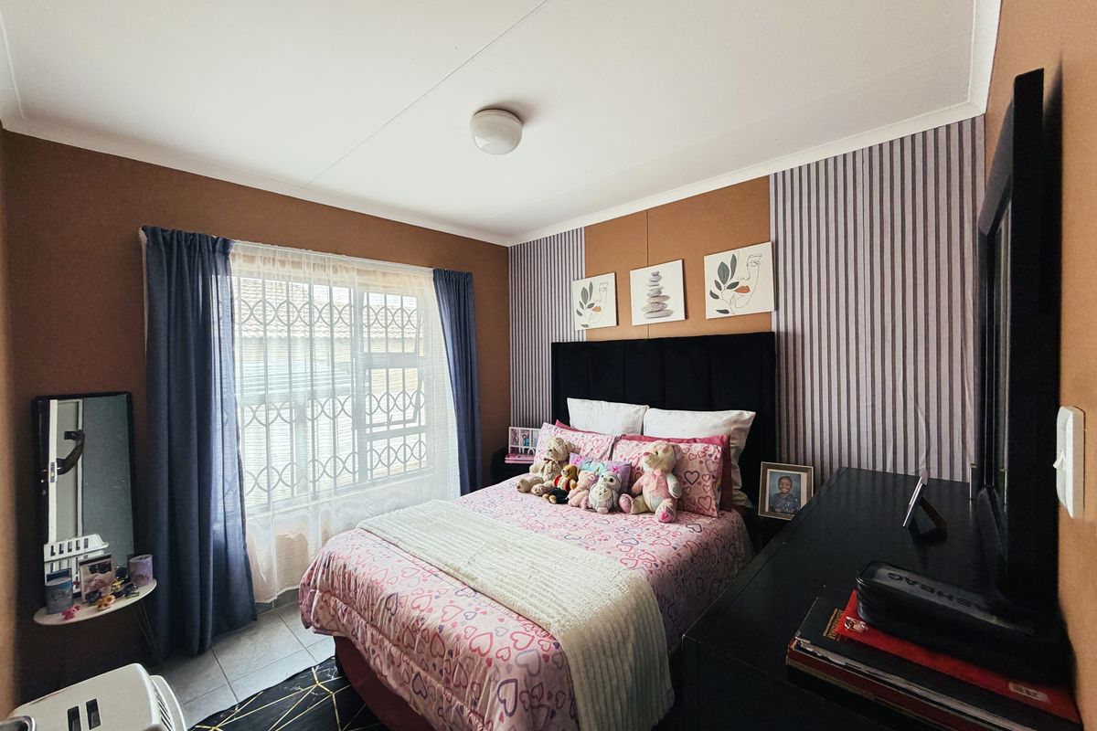 A bedroom featuring tiled flooring, a security gate on the window, and a ceiling light fixture.